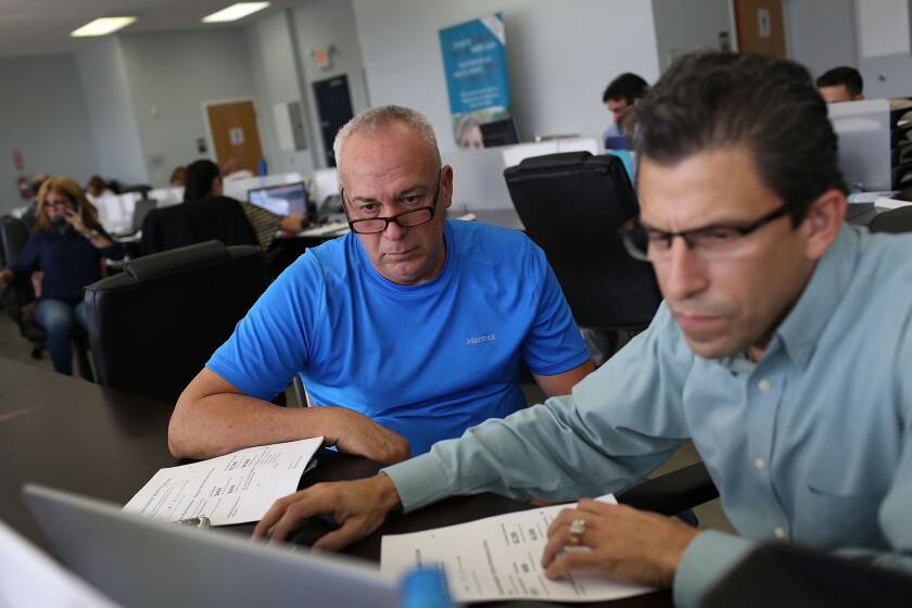 Alberto Abin, right, an insurance advisor with UniVista Insurance, helps Carlos Rodriguez shop for a health plan in Miami under the Affordable Care Act.