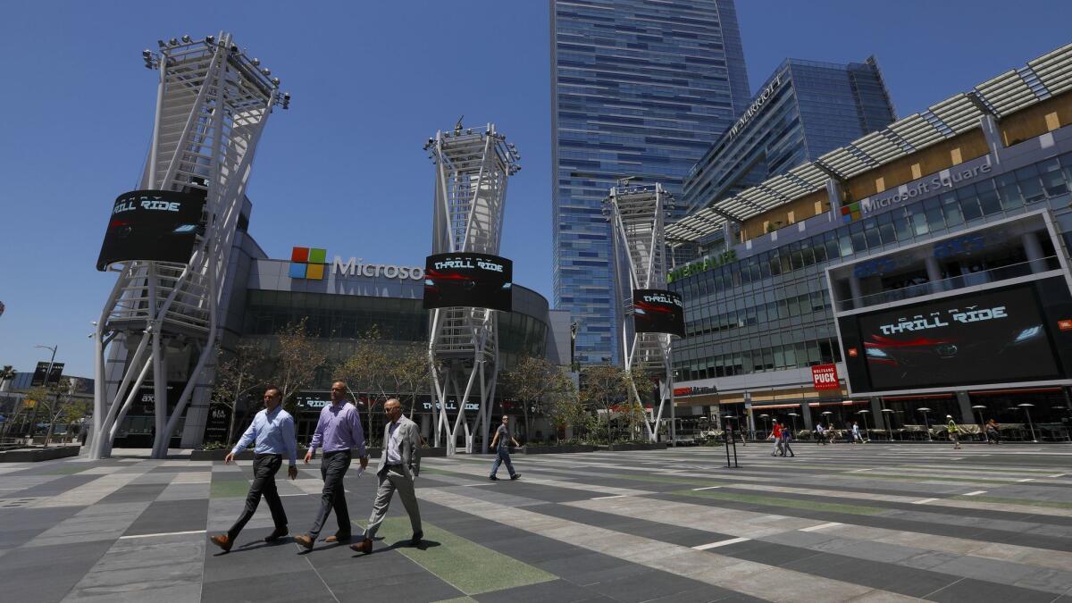 People walk through the L.A. Live complex near downtown Los Angeles in 2018. AEG is retaining ownership of that facility and its other real estate holdings.