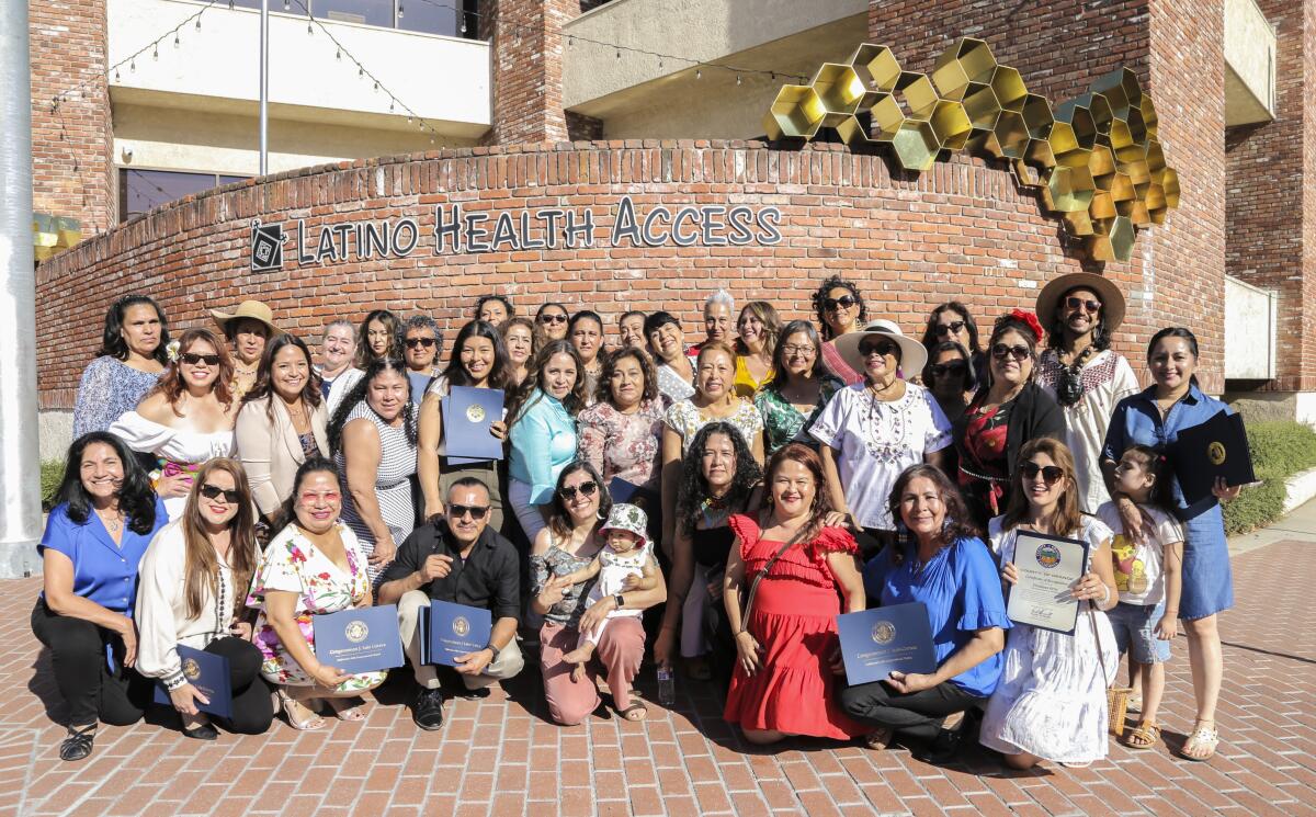 Promotorzy pozują przy mosiężnej rzeźbie w Latino Health Access po jej odsłonięciu 29 czerwca