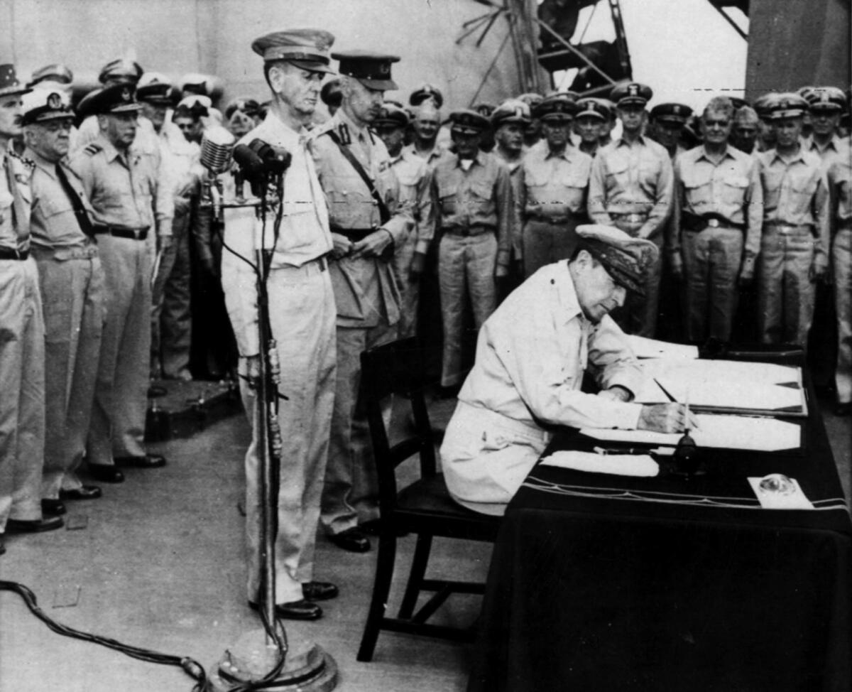 Sep. 2, 1945: Gen. Douglas MacArthur signs the Japanese surrender document aboard the Missouri in Tokyo Bay. This photo appeared in the Sep. 2, 1945, Los Angeles Times.