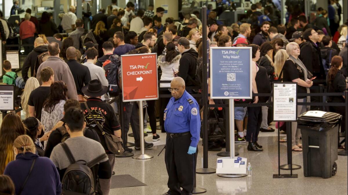 A TSA agent keeps an eye on travelers going through security at LAX.