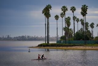 San Diego, CA - March 14: Before the expected rain arrives late Tuesday, a pair of paddlers enjoy the warm weather on a sprint canoe in the De Anza Cove of Mission Bay on Tuesday, March 14, 2023 in San Diego, CA. (Nelvin C. Cepeda / The San Diego Union-Tribune)