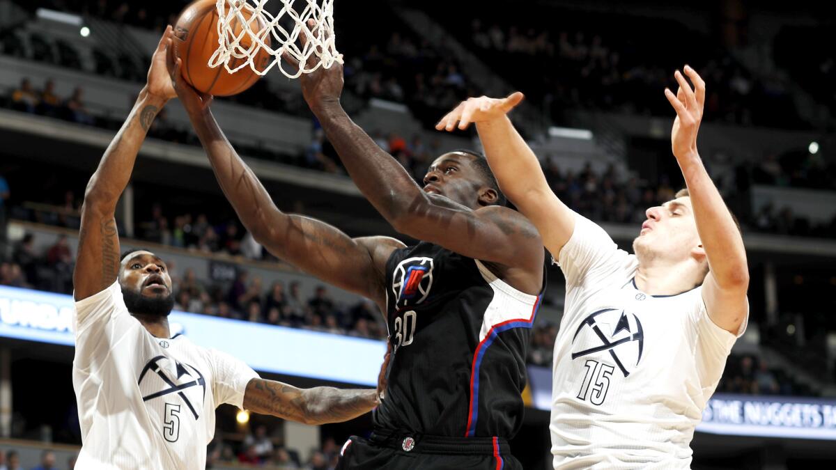 Clippers forward Brandon Bass tries to score on a drive down the lane between Nuggets guard Will Barton, left, and forward Nikola Jokic during the first half Thursday night.