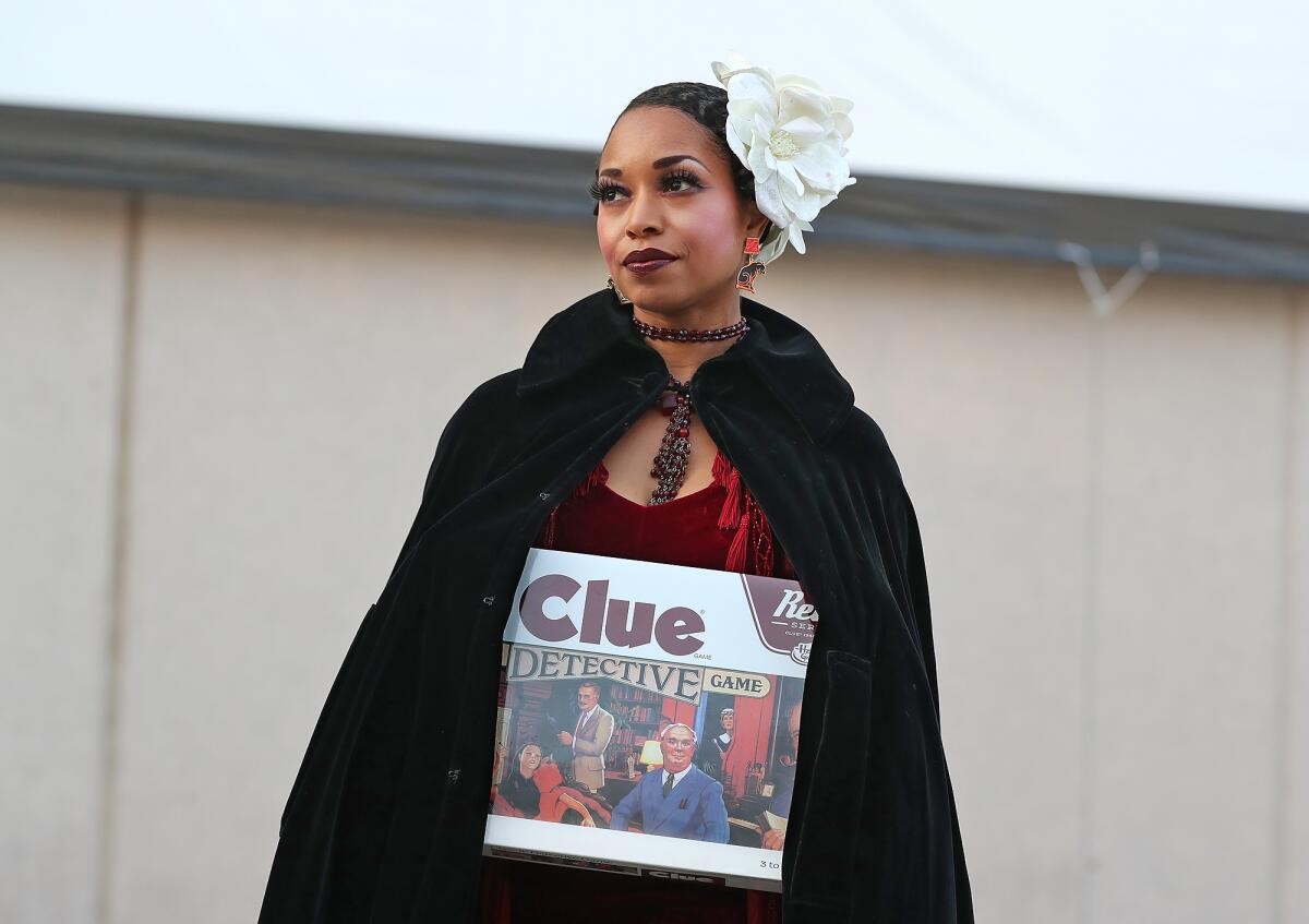 Ranitra Coleman, dressed as Miss Scarlet, holds the Clue board game during the Clue Character Costume Contest.