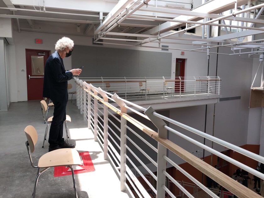 Mark Swed, wearing a face mask, takes pictures from a mezzanine overlooking a performance space