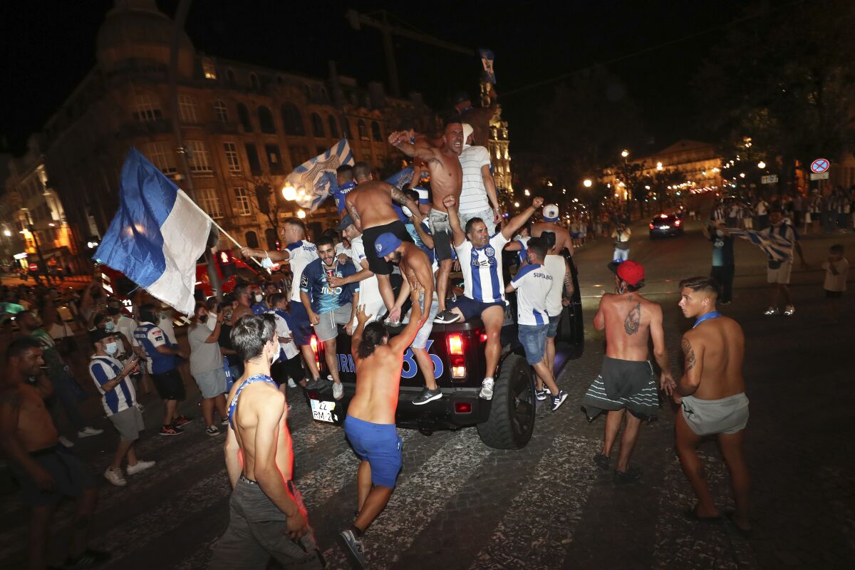 FILE - In this July 16, 2020 file photo, FC Porto fans ride on top of a vehicle while celebrating in downtown Porto, Portugal, after their team beat Sporting CP 2-0 to win the championship. Portugal is taking center stage for soccer during the next two weeks — a country where rivalries between clubs go well beyond the field of play. The decisive stages of the Champions League will begin on Wednesday Aug. 12, 2020, in the southern European nation where back-and-forth accusations and legal actions involving the country’s top teams are routine. (AP Photo/Miguel Angelo Pereira, File)
