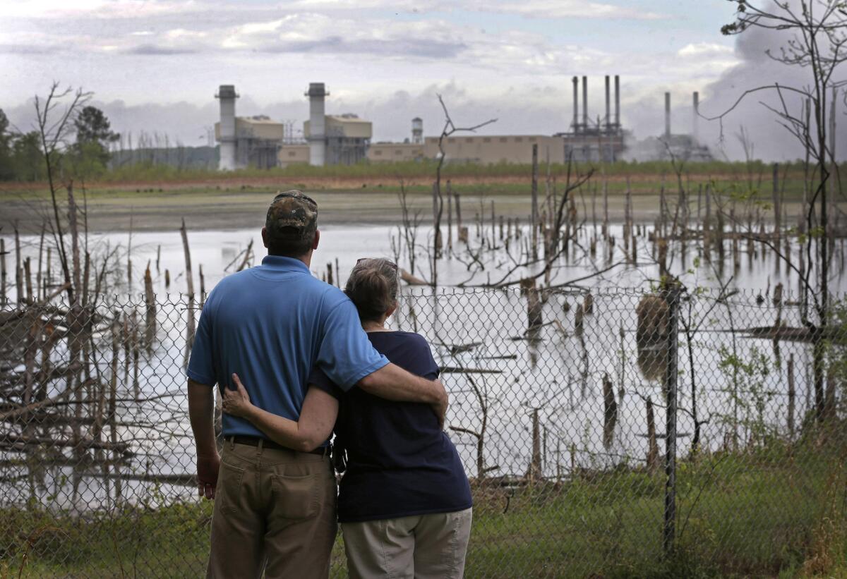 Bryant and Sherry Gobble look from their yard across an ash pond full of dead trees toward Duke Energy's Buck Steam Station in Dukeville, N.C., on April 25, 2014.