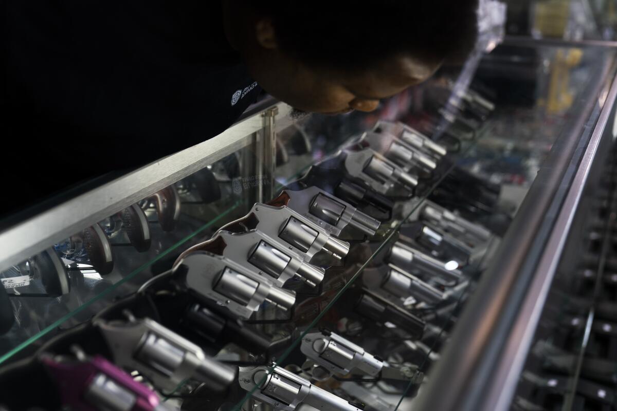 An employee arranges guns on display at Burbank Ammo & Guns.