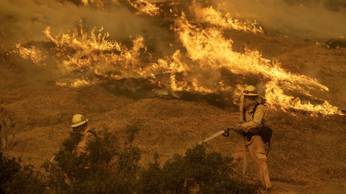 Two firefighters confront flames along Kagel Canyon Street in Lakeview Terrace.