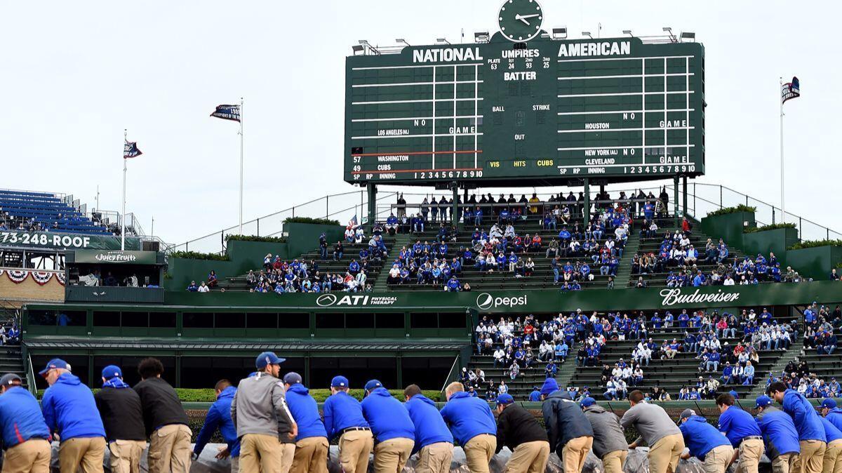 Members of the grounds crew cover the infield with a tarp Tuesday before Game 4 of the NLDS between the Washington Nationals and Chicago Cubs at Wrigley Field.