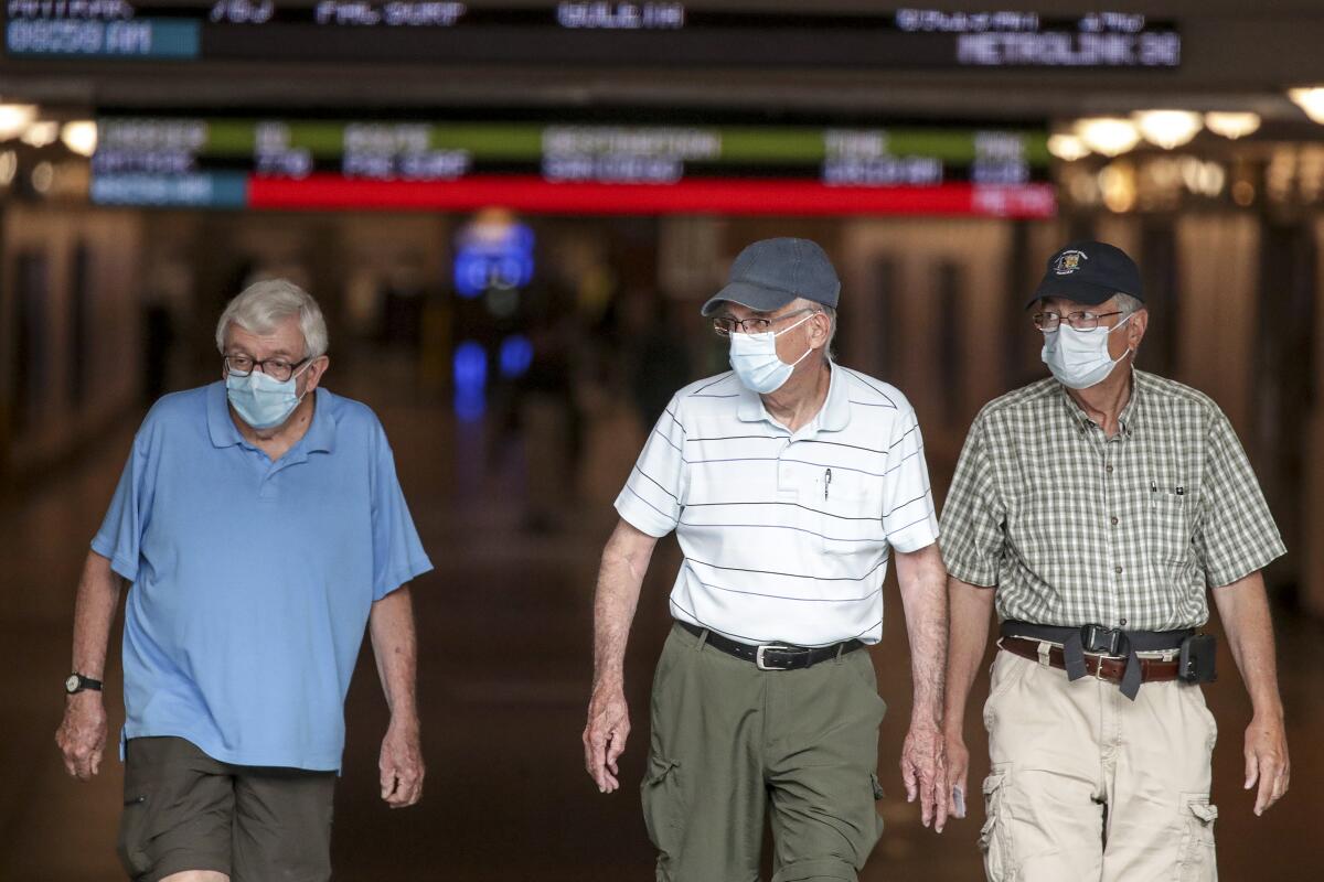 Three men walk through Union Station wearing masks.