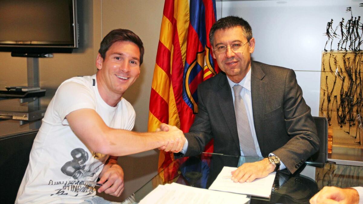 Lionel Messi, left, shakes hands with FC Barcelona President Josep Maria Bartomeu after extending his contract.