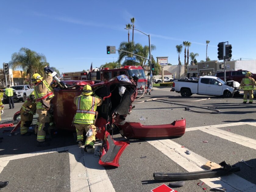 Firefighters work to extricate a person from a car that rolled over Monday at West 19th Street and Meyer Place in Costa Mesa.