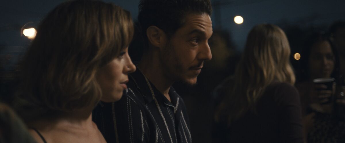 Aubrey Plaza and Theo Rossi stand side by side in a scene from "Emily the Criminal."