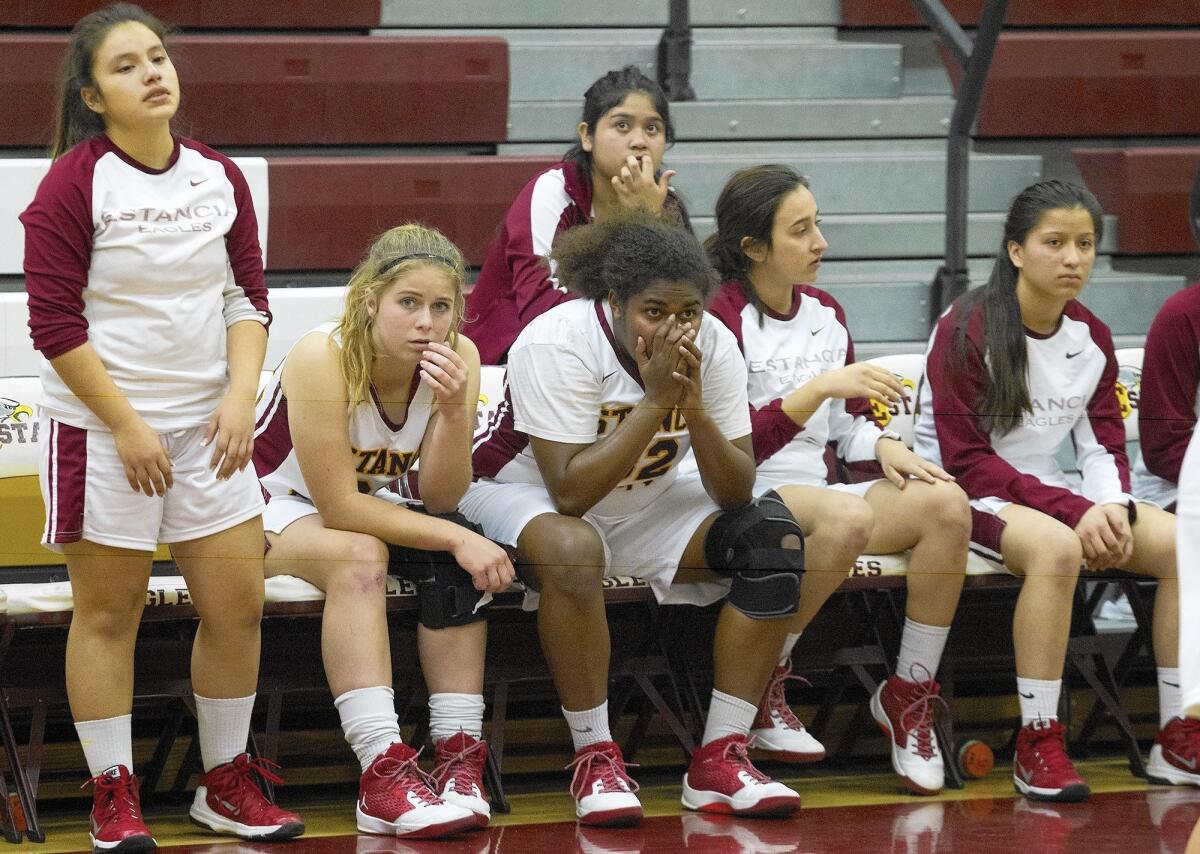 Estancia High's Maya Van Den Heever, center, looks on from the bench after fouling out during the fourth period against Laguna Beach.