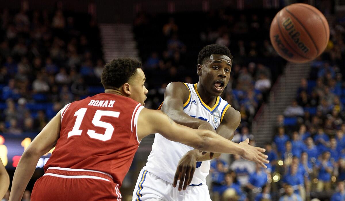 UCLA guard Aaron Holiday, center, passes the ball as Utah guard Lorenzo Bonam, left, defends during the second half on Feb. 18.