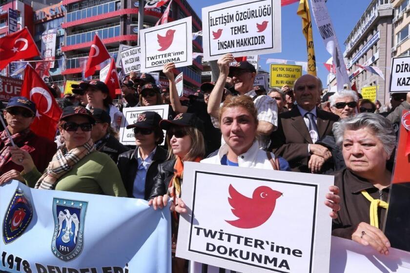 Protesters hold up signs reading "Do not touch my Twitter" and "Communication right is a basic human right" during a demonstration in Ankara, Turkey, against the ban on the Turkish government's ban on Twitter.