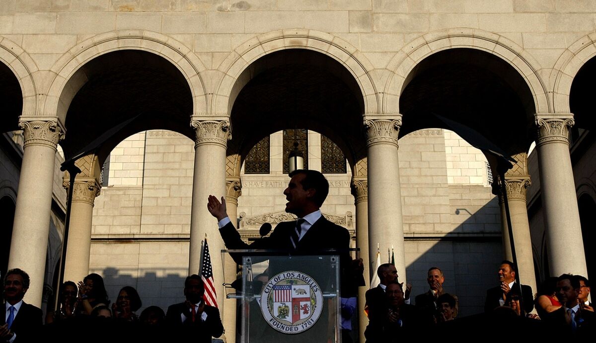 L.A. Mayor Eric Garcetti speaks at a lectern on the steps of City Hall in front of a line of people