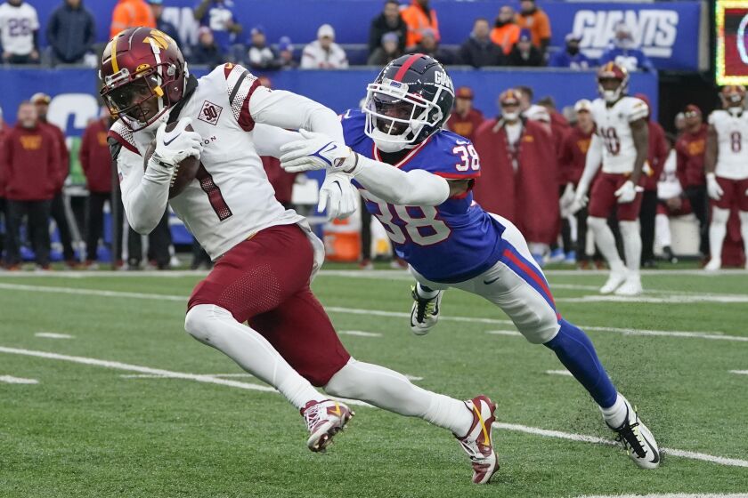 Washington Commanders' Jahan Dotson, left, runs for a touchdown while New York Giants Zyon Gilbert tries to tackle during the second half of an NFL football game, Sunday, Dec. 4, 2022, in East Rutherford, N.J. (AP Photo/John Minchillo)