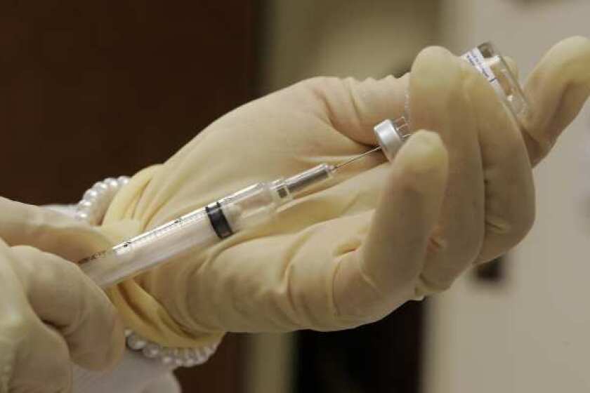 A nurse at the Travel and Adult Immunization Clinic in Pasadena fills a syringe, right, with flu vaccine.