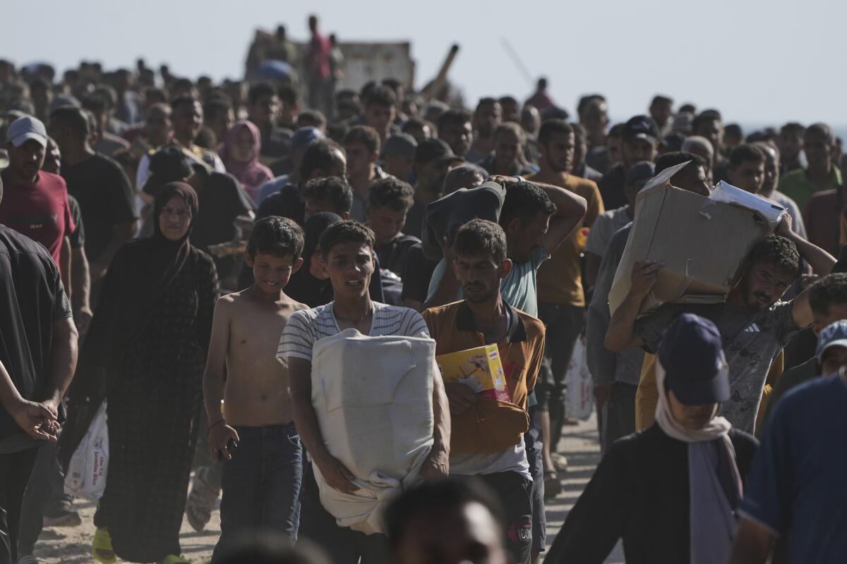 people carry boxes containing food and humanitarian aid packages