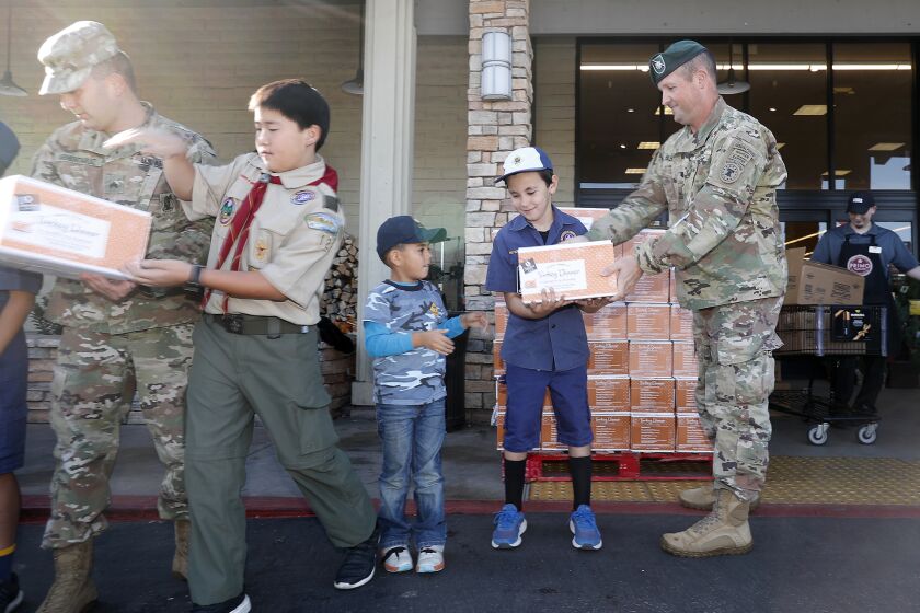 Commander John T. Bleigh, far right, passes a Thanksgiving dinner box to Dylan Amirpour, second from right, with Boy Scouts of America Laguna Hills Pack 800 as the U.S. Army Southern California Recruiting Battalion pick up more than 100 turkeys, pumpkin pies and dinner rolls from the Vons in Anaheim Hills for families of the army recruiters working in Southern California. Donations were coordinated by Yorba Linda nonprofit called For Families of Active Military.