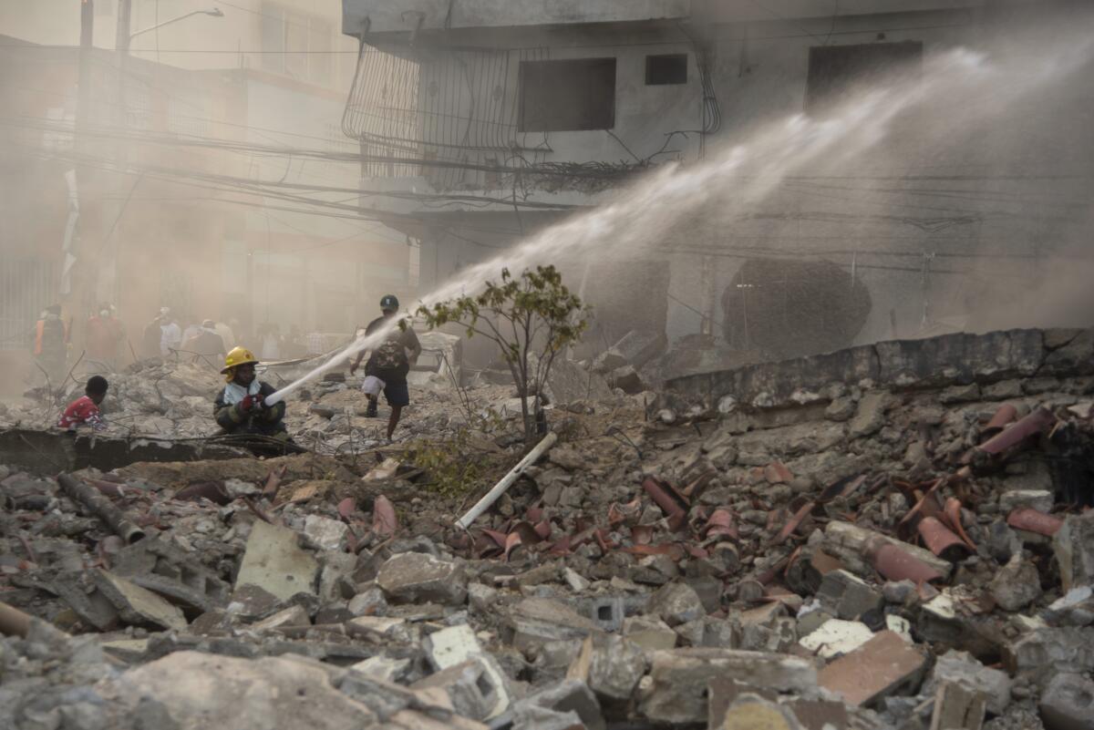 Firefighters put out a fire after a powerful explosion in San Cristobal, Dominican Republic.