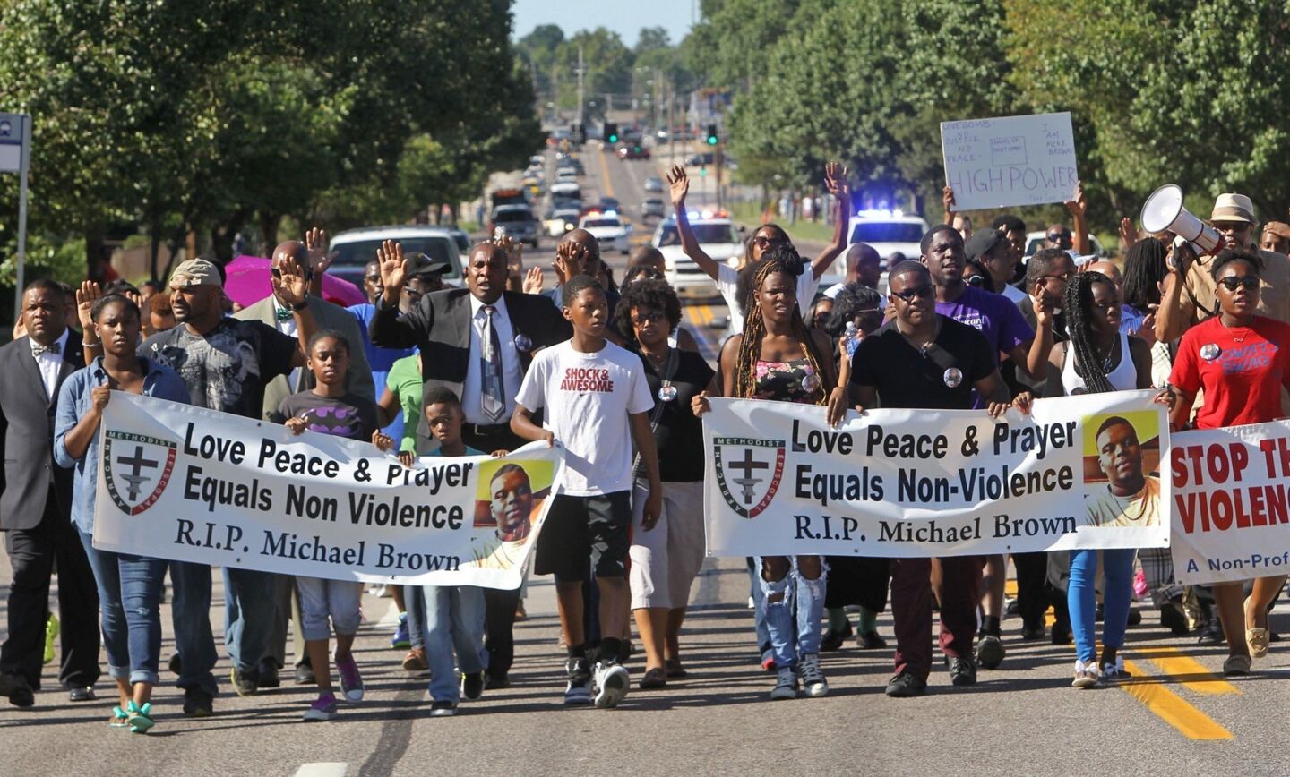 A protest march by supporters of Michael Brown moves along a Ferguson street.
