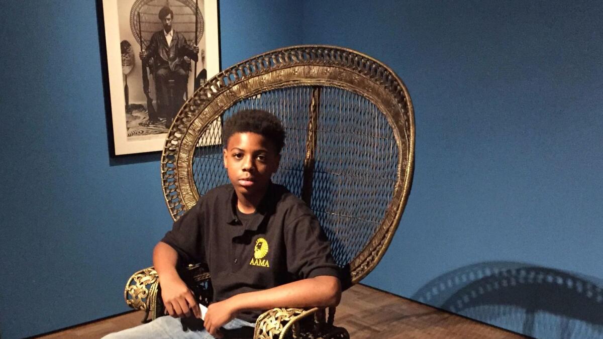 Damion Secrease, 13, visited "All Power to the People: Black Panthers at 50." He sits in a replica of the peacock chair made famous by Black Panther co-founder Huey P. Newton, shown behind him.