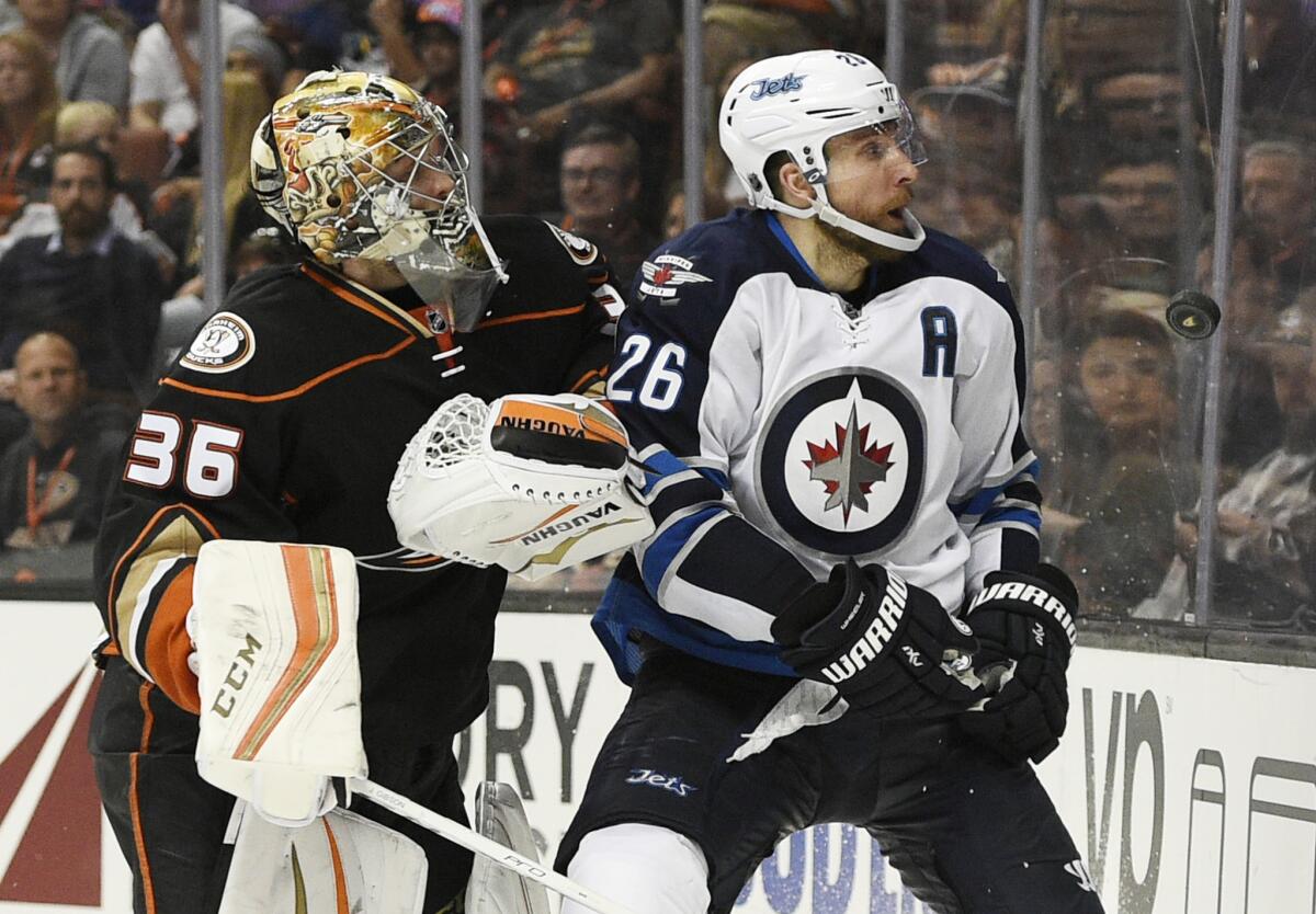 Jets forward Blake Wheeler, right, knocks the puck up and away from Ducks goalie John Gibson during the third period of a game on April 5.