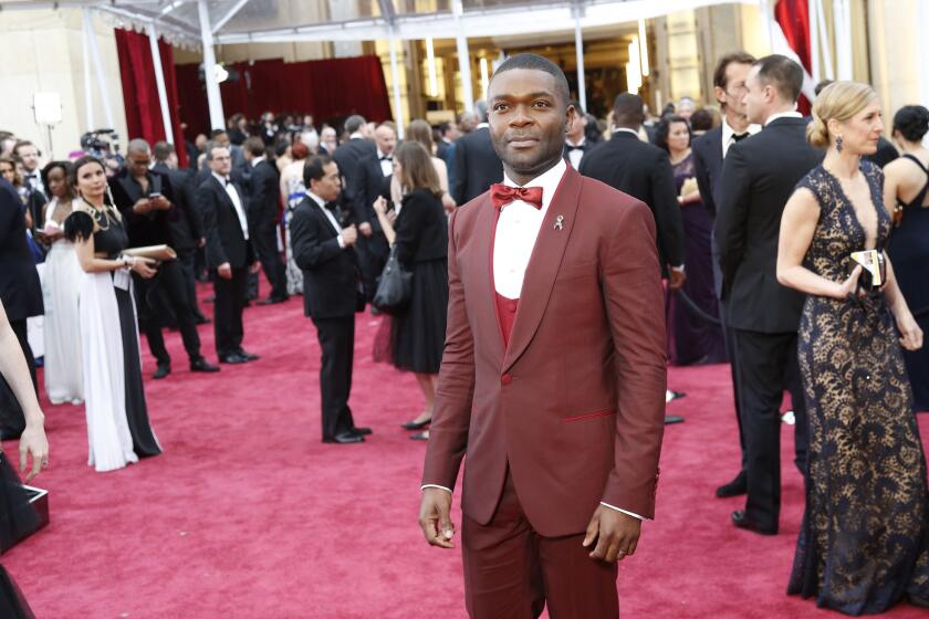 David Oyelowo stands out out on the red carpet in a red shawl collar tuxedo with a red silk bow tie and red cummerbund.