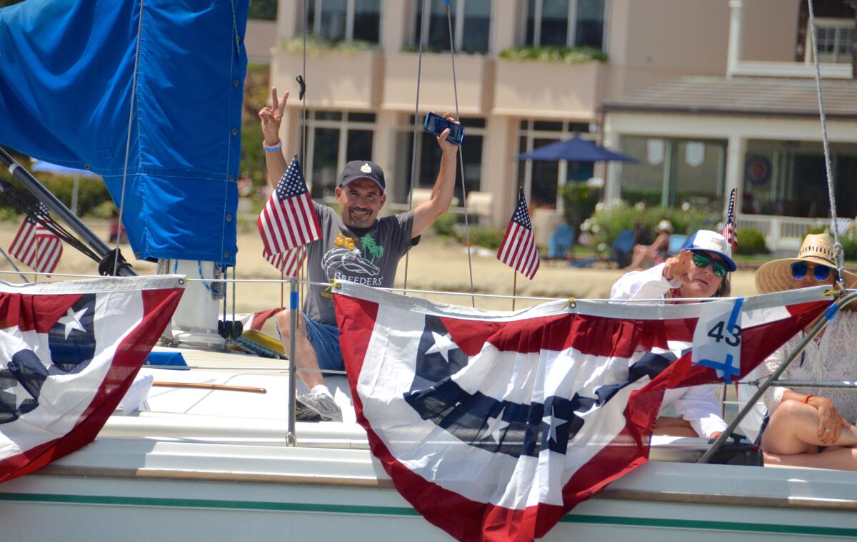 Grace Anne sailboat riders wave to beachgoers during Old Glory boat parade on the Fourth of July.