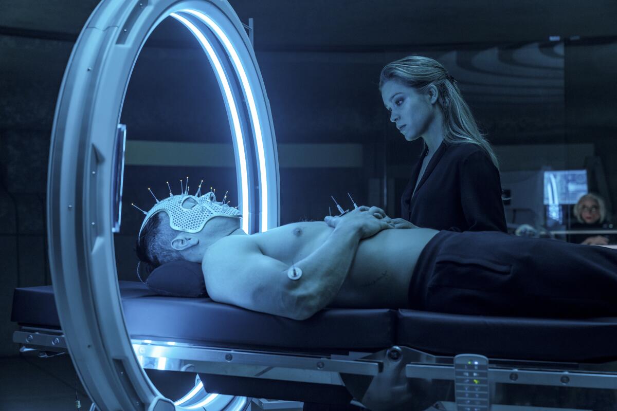 Mark Wahlberg tests out some high-tech acupuncture while Sophie Cookson looks on in the movie "Infinite."