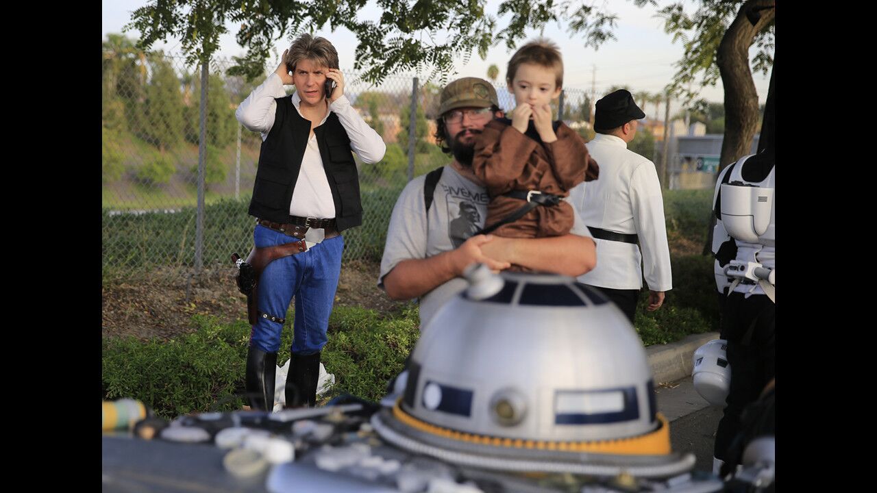 Jeff Donoho, left, is dressed as Han Solo, as Nathan Tebo, 5, and his father, Michael Tebo, view the "Obishawn" decorated car as they join the Friends of the Mouse Disneyland fan club dressed in homemade "Star Wars" costumes during the Anaheim Halloween Parade on Saturday.