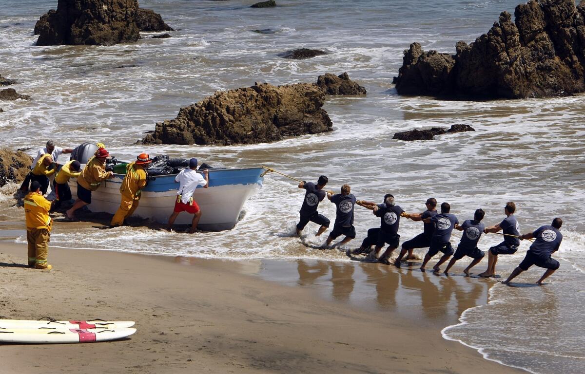Firefighters pull a beached panga-style boat back into the water at Leo Carrillo State Beach in Malibu on Monday. The boat was seized after it washed ashore. Authorities said it was loaded with as much as a ton of marijuana.