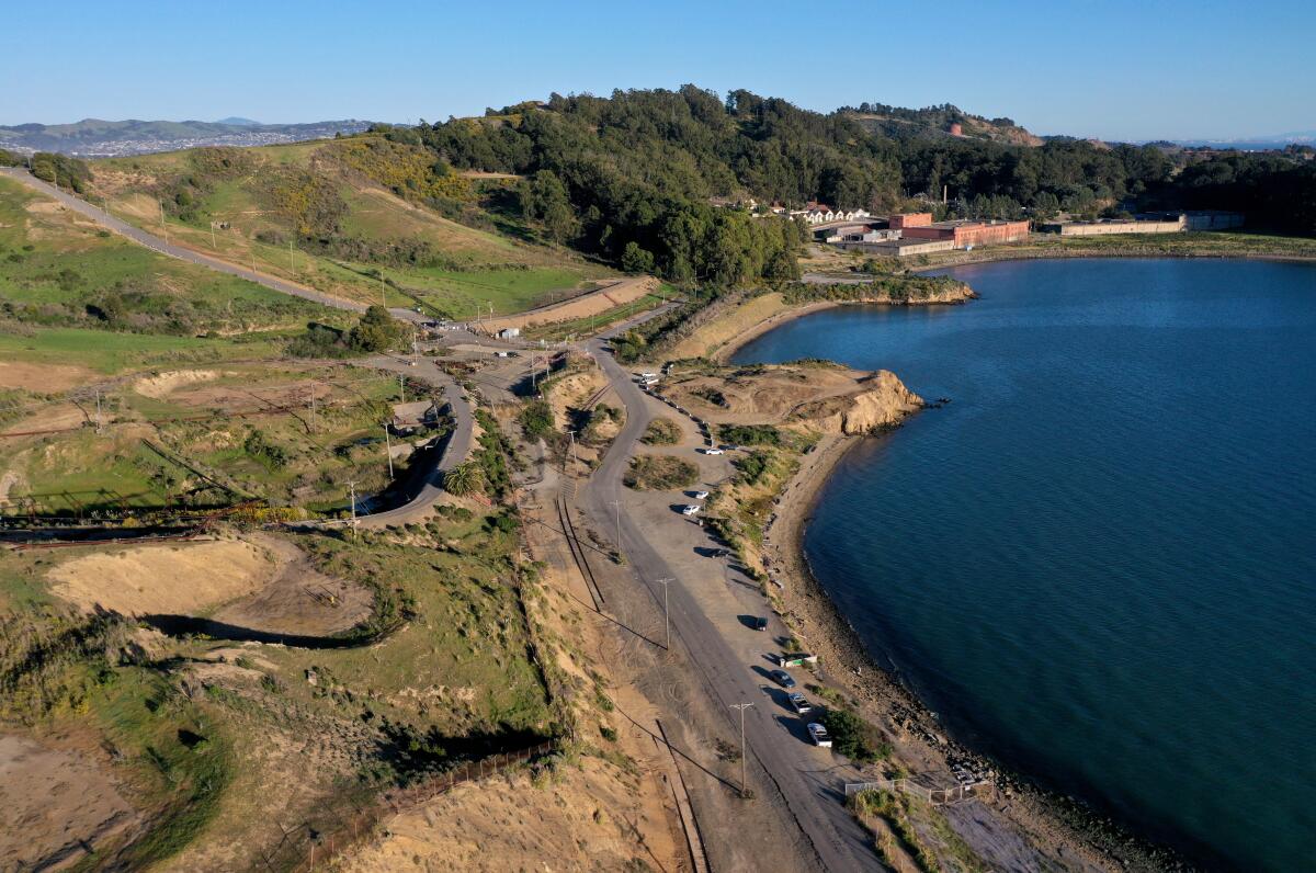 An aerial photograph of shoreline hills, trees, water and distant buildings 