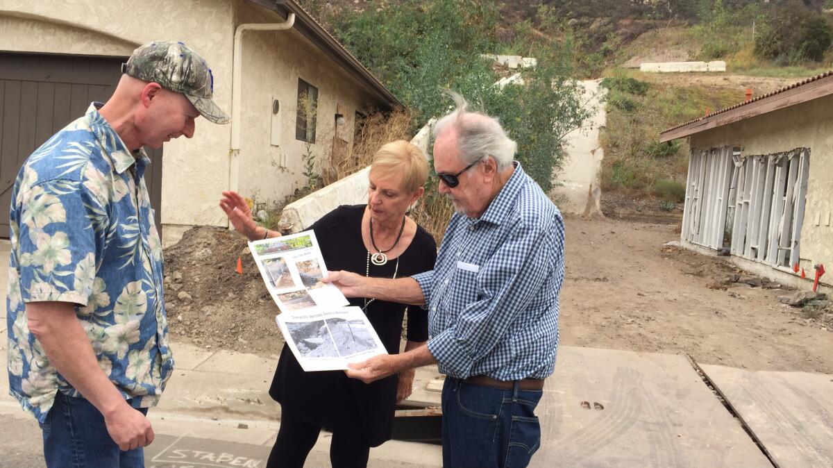 Camarillo Springs HOA board members Barry Gilbert, Val Palmer and Pete Faxon look over photos of the destruction while at the slide location nearly two years later.