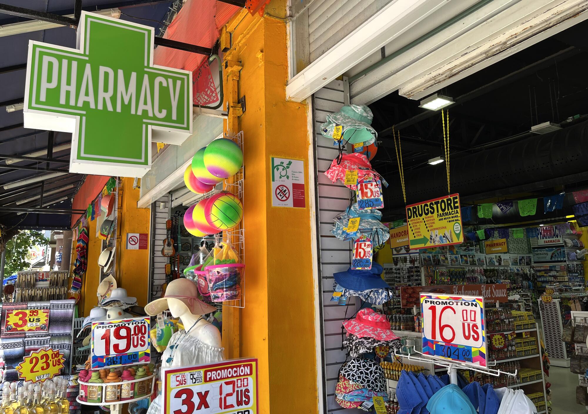 A pharmacy sign hangs over assorted merchandise outside a store.