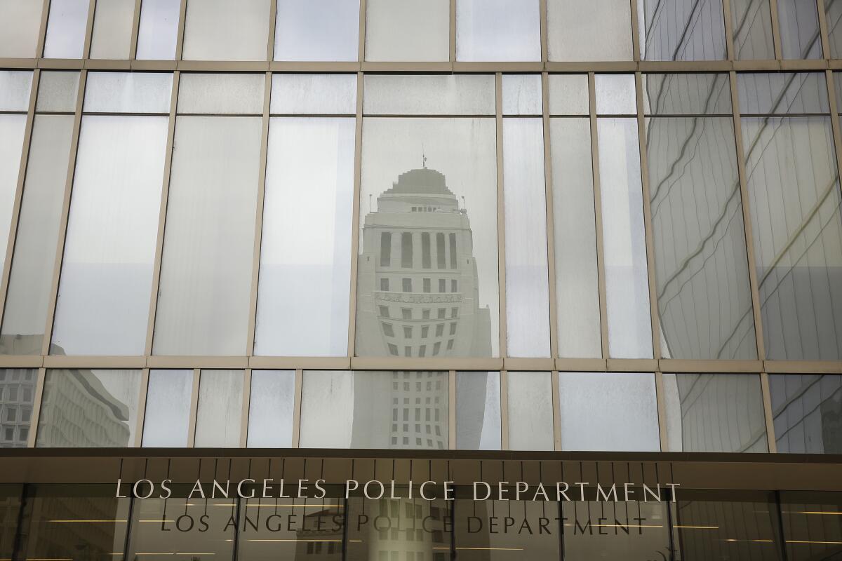 The L.A. City Hall tower is reflected in the windows of the LAPD headquarters.