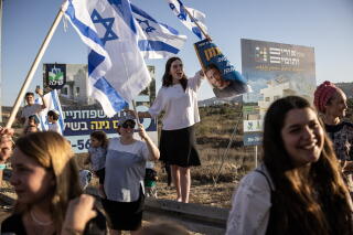 A group of people cheering, some waving blue and white flags with a blue star