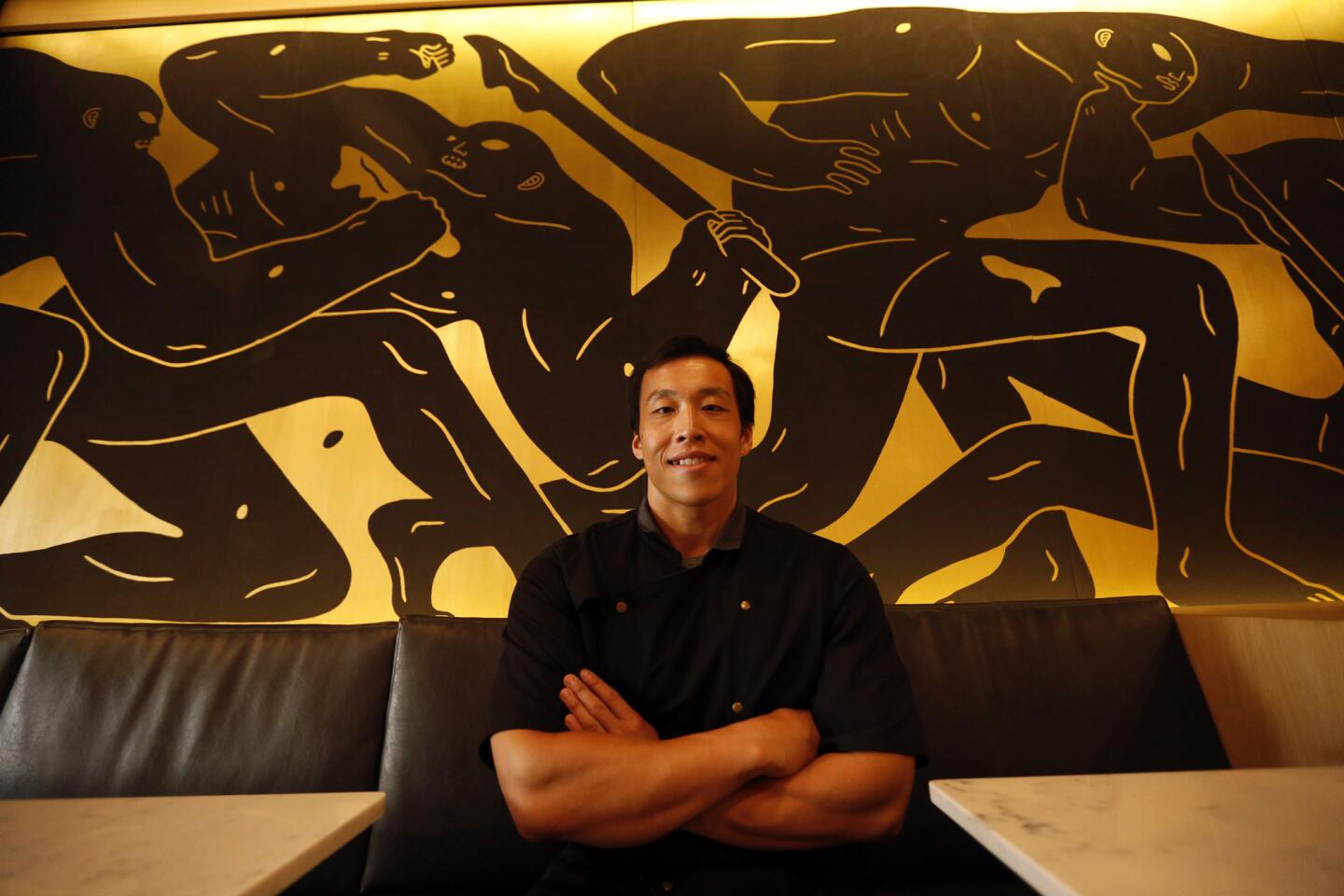 Chef Erwin Tjahyadi sits in front of a mural by artist Cleon Peterson that anchors the main dining r