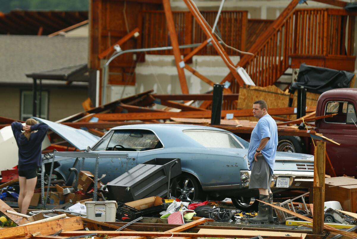 A man and woman inspect the damage to their home and classic cars after a tornado hit near Lawrence, Kan.