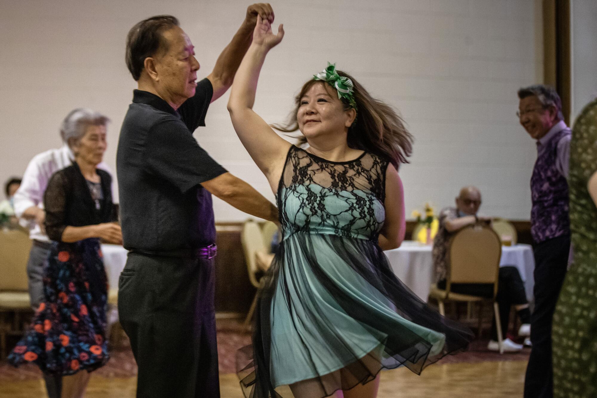 A man spins a woman around as they dance.