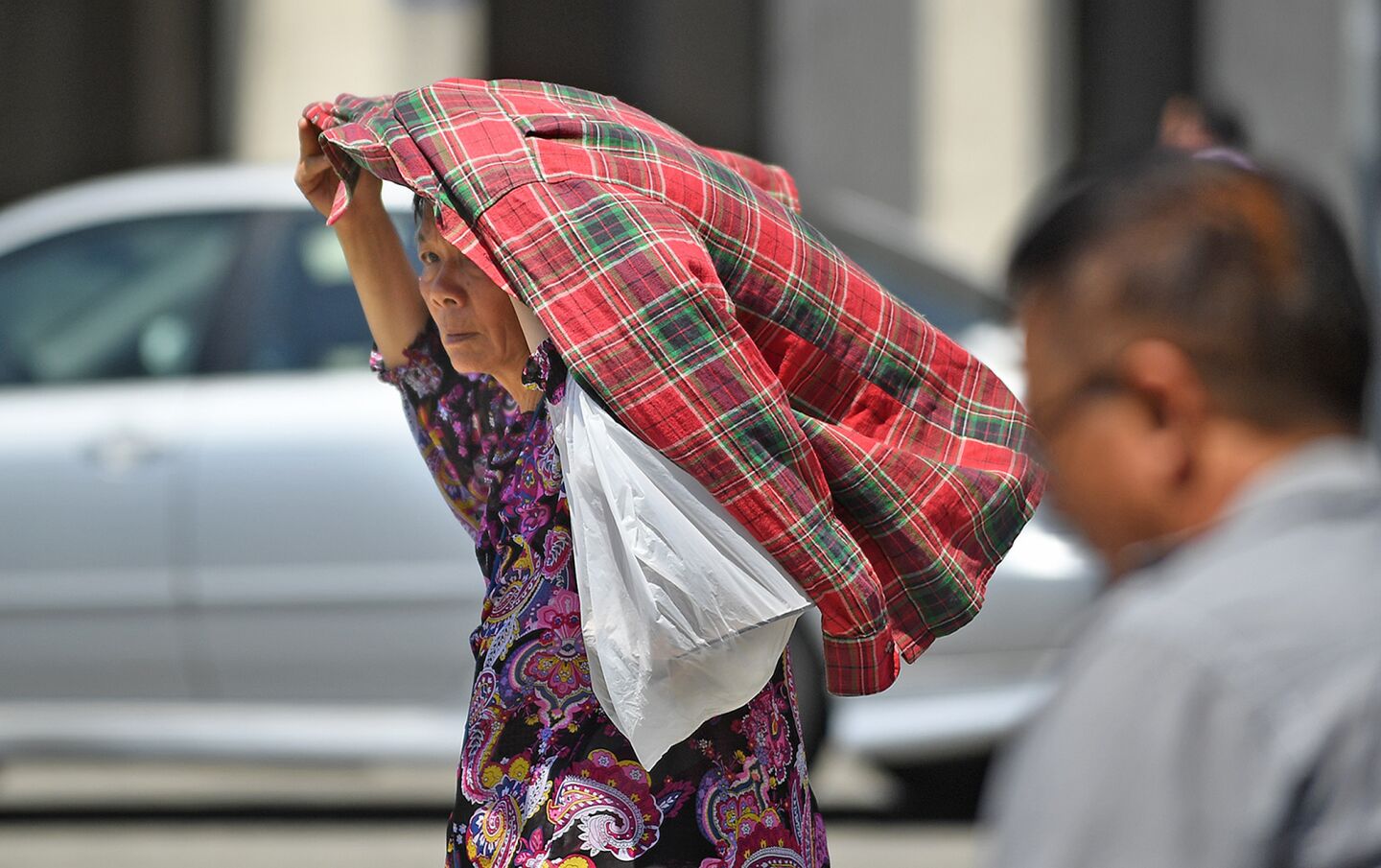 A woman shields herself from the hot sun in 91 degree weather in Chinatown.