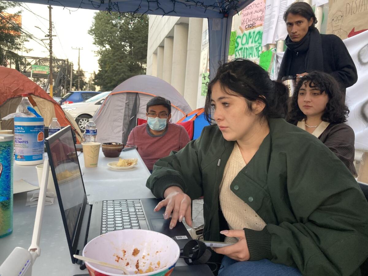 A student protestor sits at her laptop