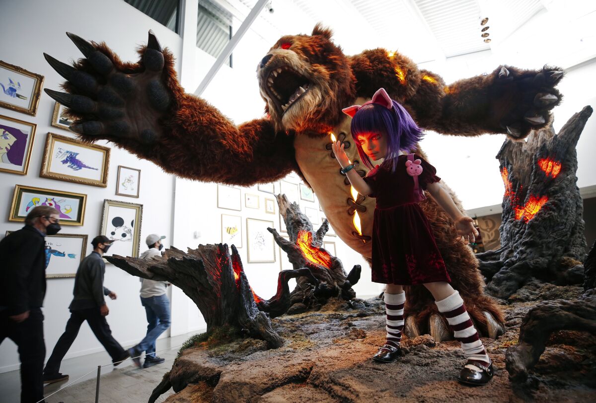 A statue with a furry figure with long claws and a small girl with striped socks and purple hair.