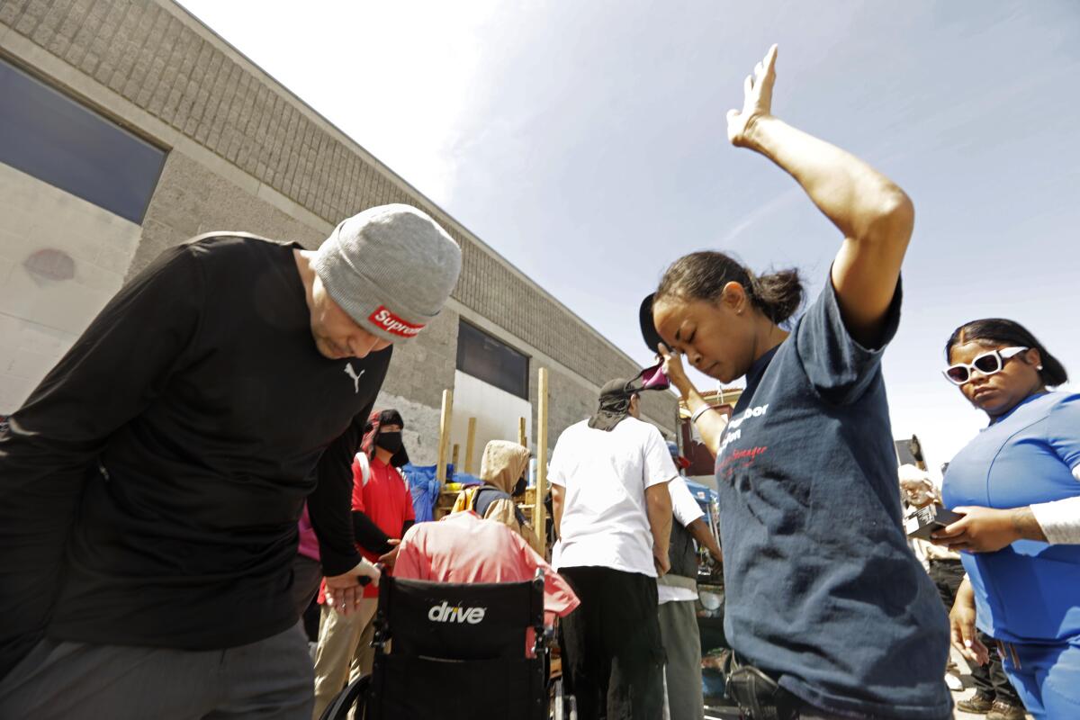 People joins in a prayer at weekly food giveaway along 7th Street in Skid Row.
