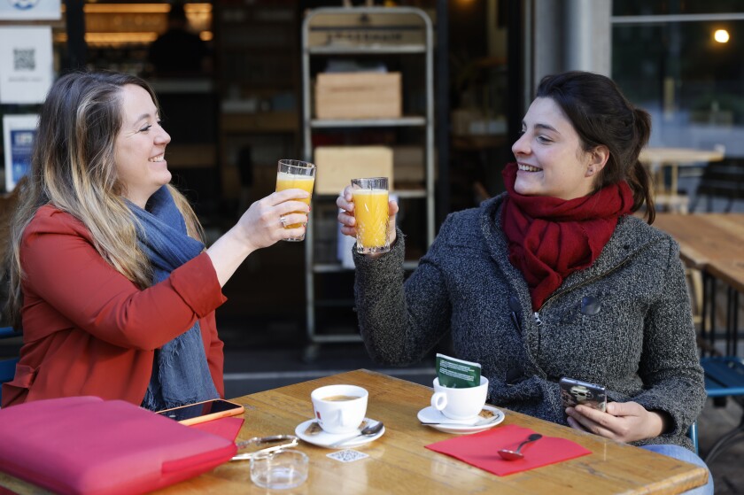 Women enjoy a cafe and an orange juice at a café terrace Wednesday, May, 19, 2021 in Strasbourg, eastern France. It's a grand day for the French. Café and restaurant terraces are reopening Wednesday after a shutdown of more than six months deprived people of what feels like the essence of life — sipping coffee and wine with friends outdoors — to save lives during the coronavirus pandemic. (AP Photo/Jean-Francois Badias)