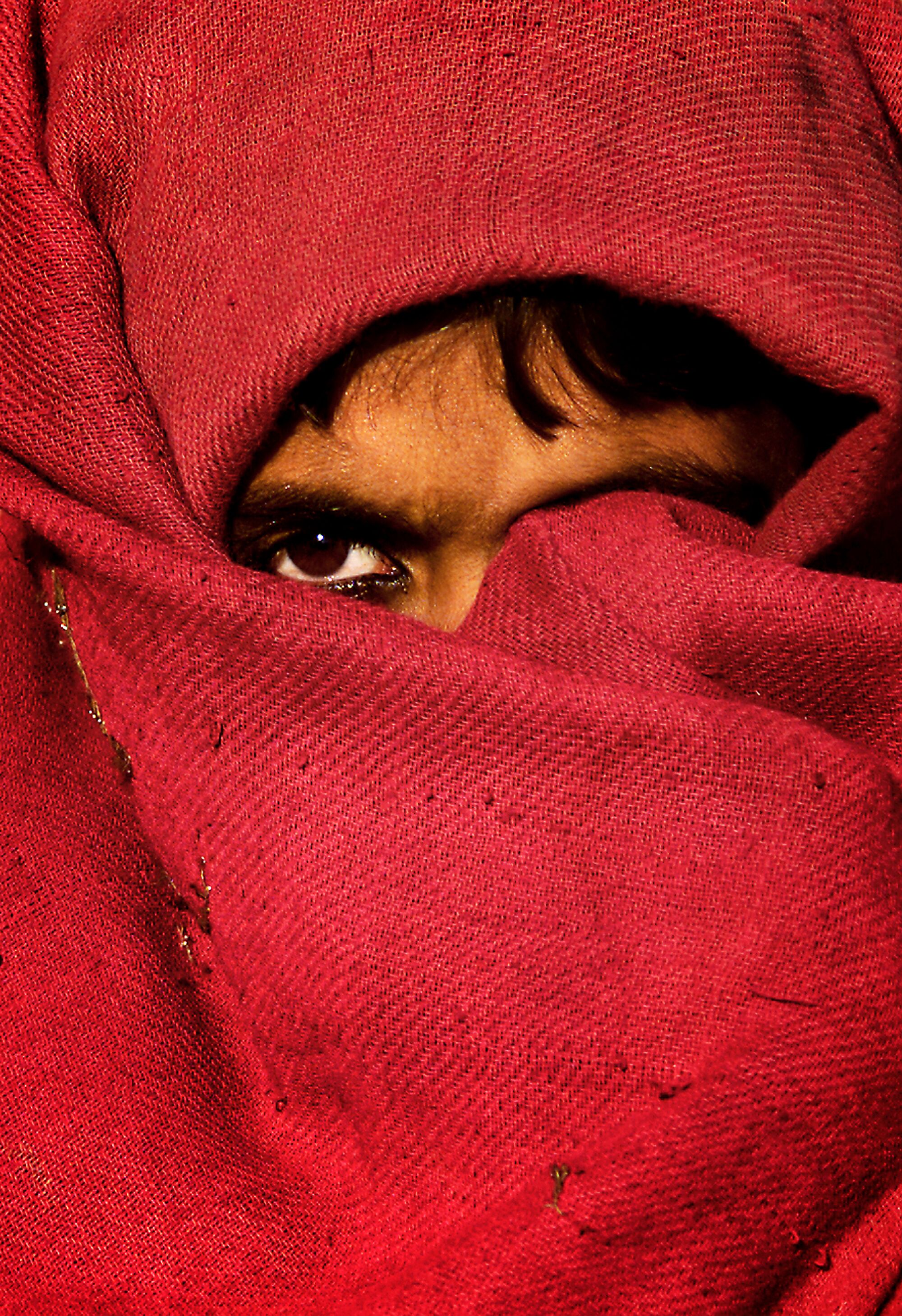 A girl with her face mostly covered by red cloth