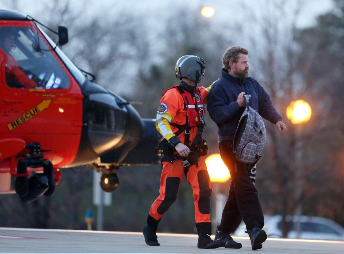 Louis Jordan, right, walks from the Coast Guard helicopter to the Sentara Norfolk General Hospital in Norfolk, Va., after being found off the North Carolina coast Thursday after two months adrift.